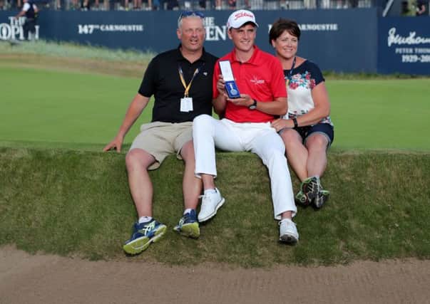 Sam Locke perches on the edge of the 18th green at Carnoustie with his parents and holds his silver medal for finishing best amateur. Picture: Richard Sellers/PA