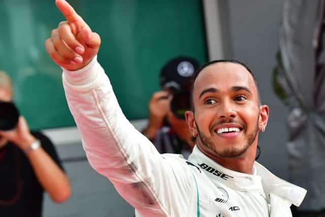 Sebastian Vettels Ferrari is lifted out of the gravel, while Lewis Hamilton,left, celebrates his famous victory. Picture: AFP/Getty.