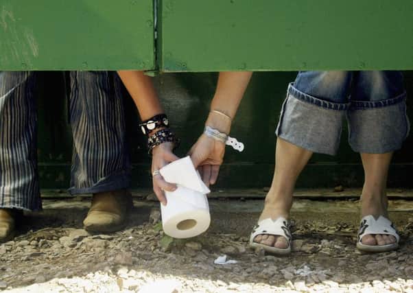 Two festival goers pass a roll of toilet paper between cubicles. Picture: Matt Cardy/Getty Images