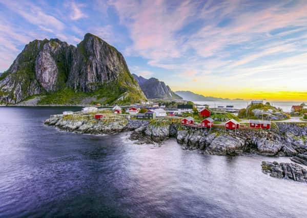 Popular view of Fishing hut (rorbuer) in Hamnoy, Norway with Lilandstinden mountain peak as the background during sunrise.