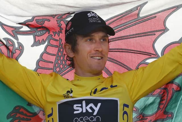 Britain's Geraint Thomas, wearing the overall leader's yellow jersey, holds the Welsh flag on the podium after the twenty-first stage of the Tour de France cycling race over 116 kilometers (72.1 miles) with start in Houilles and finish on Champs-Elysees avenue in Paris, France, Sunday July 29, 2018. (AP Photo/Christophe Ena )