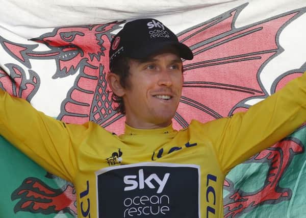 Britain's Geraint Thomas, wearing the overall leader's yellow jersey, holds the Welsh flag on the podium after the twenty-first stage of the Tour de France cycling race over 116 kilometers (72.1 miles) with start in Houilles and finish on Champs-Elysees avenue in Paris, France, Sunday July 29, 2018. (AP Photo/Christophe Ena )