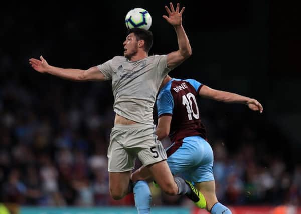 Scott McKenna (left) and Burnley's Ashley Barnes battle for the ball at Turf Moor. Picture: PA