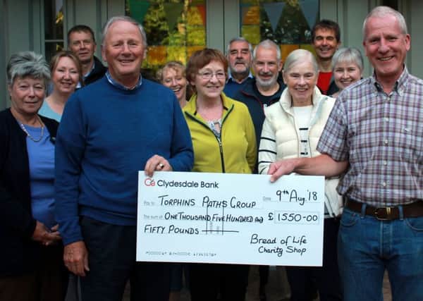 Stewart Keir is pictured presenting the cheque to Will Mclean, with shop and path group representatives present.
