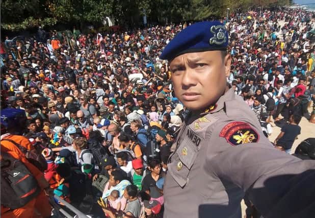 Chief of the water police of Lombok, Dewa Wijaya, taking a picture in front of hundreds of people attempting to leave Gili Trawangan, north of neighbouring Lombok island, a day after a 6.9 magnitude earthquake struck the area.
 Picture: AFP PHOTO / Indonesia Water Police /Getty Images