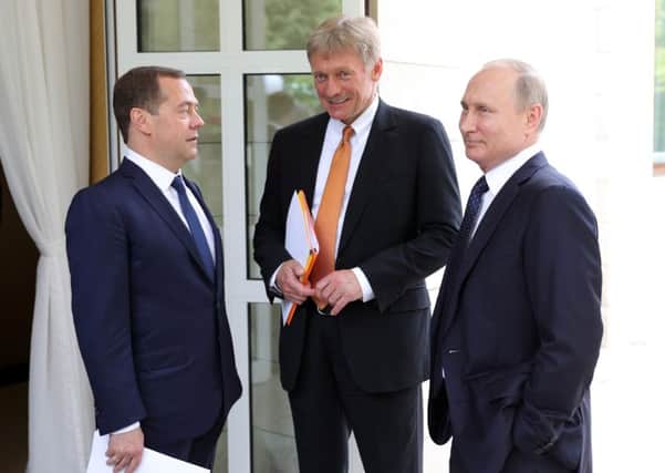 Russian President Vladimir Putin (R), presidential spokesman Dmitry Peskov (C) and Prime Minister Dmitry Medvedev (L) speak before a meeting with the German Chancellor in Sochi. Picture: Mikhail Klimentyev/AFP/Getty