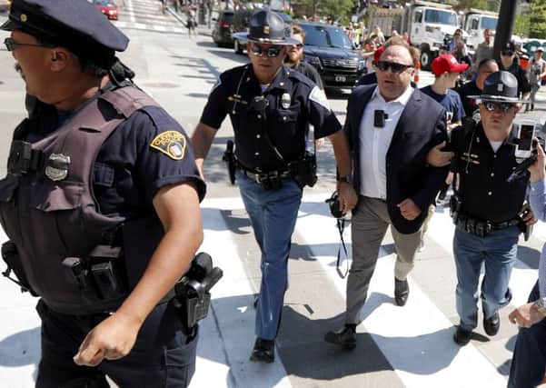 Alex Jones being escorted by police out of a crowd of protesters outside a Republican convention in Cleveland. Picture: 
John Minchillo/AP