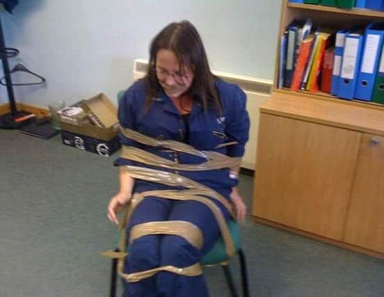 A woman who complained of a racist and misogynistic culture in a Scottish government department claims she was taped to a chair and gagged by two male colleagues.