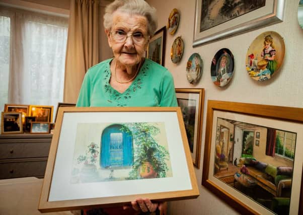 Margaret McNeil shows off one of the many hundreds of paintings she has completed since losing her sight