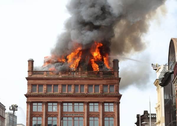A firefighter trains a hose on a major blaze which has broken out at the Primark store in Belfast city centre. Picture: PA Wire
