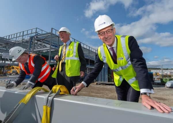 Provost of Aberdeenshire Bill Howatson, Deputy First Minister John Swinney and Derek Shewan, Chief Executive Officer of Robertson Construction sign the final beam before it was lifted into place