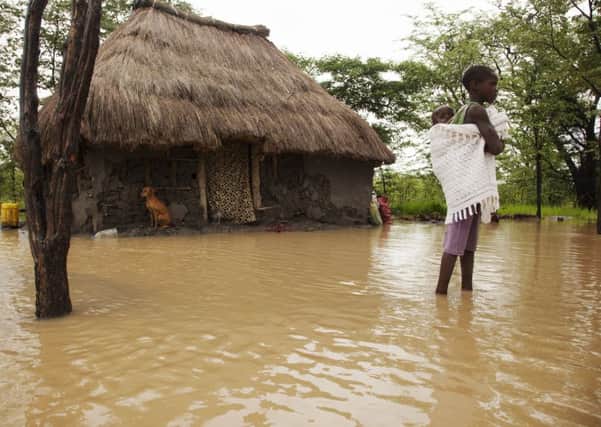 A child carrying a baby outside a flooded house in Zambia