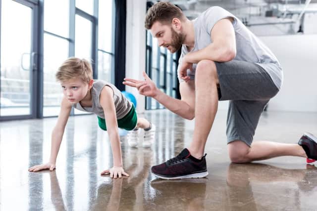 A boy does push-ups under the watchful eyes of a trainer