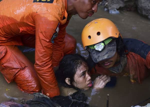 Rescuers help a traumatised survivor from a damaged house in the city of Palu in central Sulawesi yesterday after the earthquake and tsunami struck in Indonesia 
on Friday. Picture: AP Photo/Arimacs Wilander