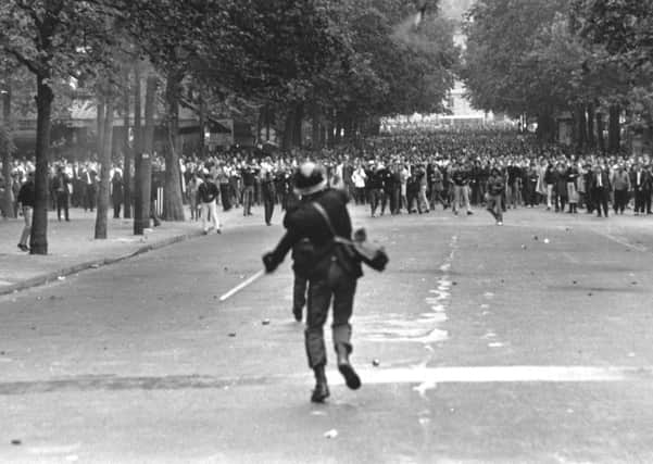 A policeman throws a tear gas canister to disperse crowds during student riots in Paris in 1968. Picture: Reg Lancaster/Getty Images