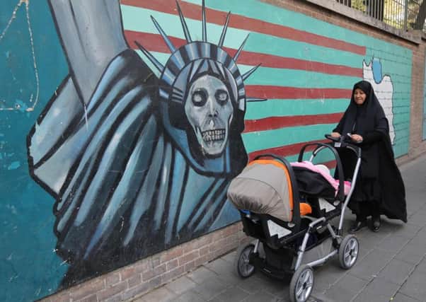 An Iranian woman walks past graffiti on the walls of the former US embassy in Tehran (Picture: Atta Kenare/AFP/Getty)