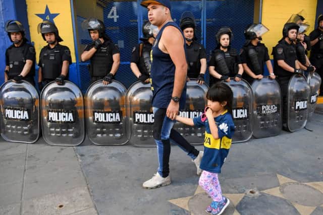 Riot police outside the ticket office at Boca Juniors' La Bombonera stadium as a fan and his young daughter walk past. Picture: Eitan Abramovich/AFP/Getty