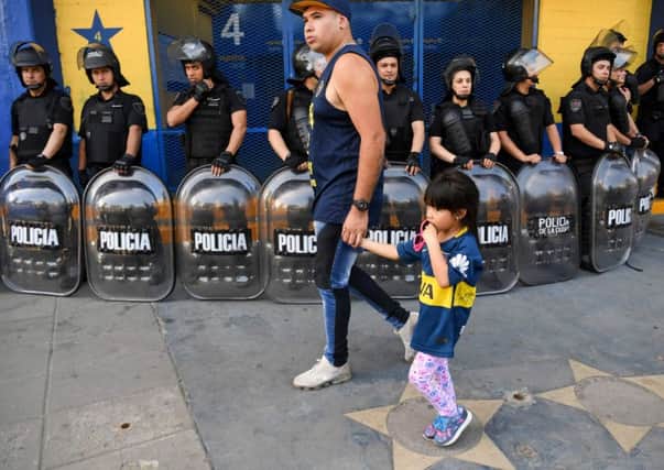 Riot police outside the ticket office at Boca Juniors' La Bombonera stadium as a fan and his young daughter walk past. Picture: Eitan Abramovich/AFP/Getty
