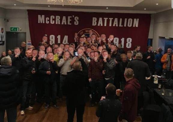 A group pose with Tommy Robinson masks in front of a McCraes Battalion Hearts flag. Picture: Instagram/realtommyrobinson