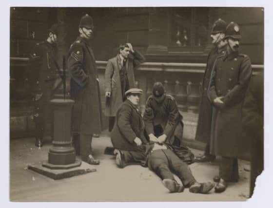 David Kirkwood (before he became MP) on the ground after being batoned by police, while Willie Gallacher stands by after being arrested, Glasgow, 1919.