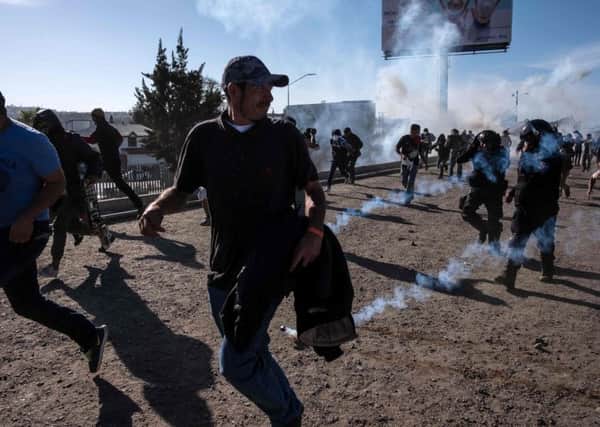 Migrants run along the dry Tijuana River near the US-Mexico border after US border guards threw tear gas to disperse them (Picture: Guillermo Arias/AFP/Getty)