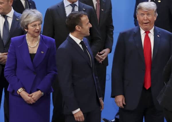 British Prime Minister Theresa May alongside French president Emmanuel Macron and US leader Donald Trump as they prepare to pose during a working session prior to the G20 Summit. Picture: Ludovic Marin/Getty Images