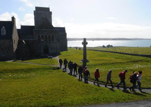 The pilgrims lave the Abbey and walk past the Cross of St Martin with its deep shadow. Picture: Robert Perry