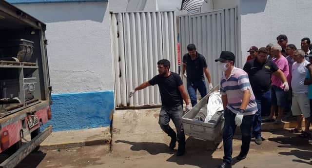 Forensic experts carry a corpse to be transported to the morgue after an attempted bank robbery in Milagres (Photo by Normando SORACLES / Agencia Miseria / AFP)