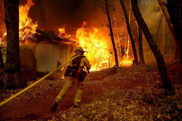 A firefighter pulls a hose towards a burning home in California. Picture: Getty