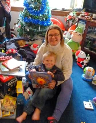 Julie Muir and her three year old son Rhys pictured in her mother's sitting room, which has been taken over with
toys and clothes donated by wellwishers after the fire at the family home destroyed their possessions including
Christmas presents. Picture: Moira Kerr.