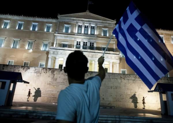 A man waves a Greek flag outside parliament after Greeks rejected an EU austerity plan in a 2015 referendum (Picture: Iakovos Hatzistavrou/AFP/Getty)