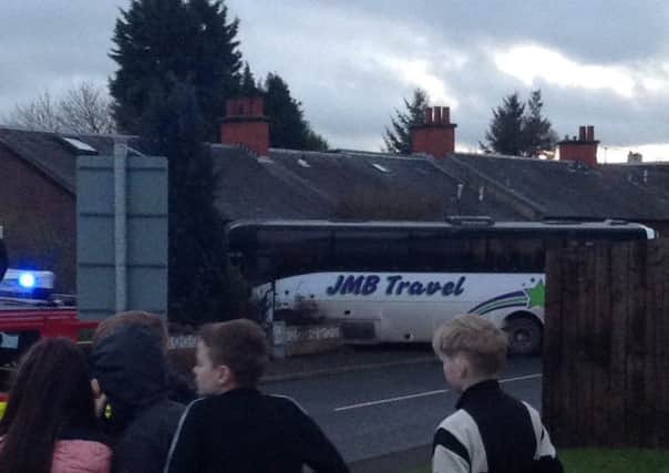Locals look on at the schoolbus crashed into a Coatbridge house. Picture: Callum Duffy