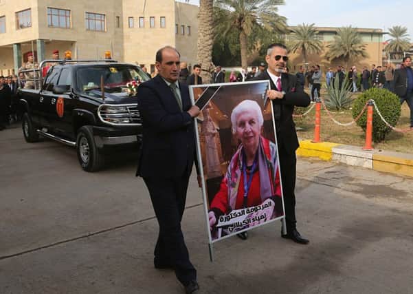 Mourners transport the flag-draped coffin of Iraqi archaeologist, Lamia al-Gailani, seen in the poster, for burial during her funeral procession in the National Museum in Baghdad  (Picture: AP Photo/Khalid Mohammed)
