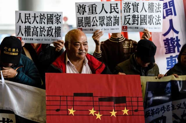 A pro-democracy activist holds a placard depicting part of the musical score of the Chinese national anthem during a protest outside the Legislative Council in Hong Kong (Picture: Anthony Wallace/AFP/Getty)