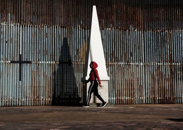 A woman walks past the border fence in the city of Tijuana, Mexico, on January 19, 2019 PIC: Spencer Platt/Getty Images