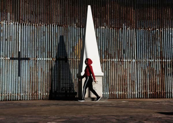 A woman walks past the border fence in the city of Tijuana, Mexico, on January 19, 2019 PIC: Spencer Platt/Getty Images