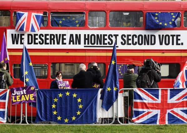 Pro-Brexit protestors stand on the pavement as a London bus decorated with anti-Brexit slogans drives past outside the Houses of Parliament. Picture: Leon Neal/Getty Images