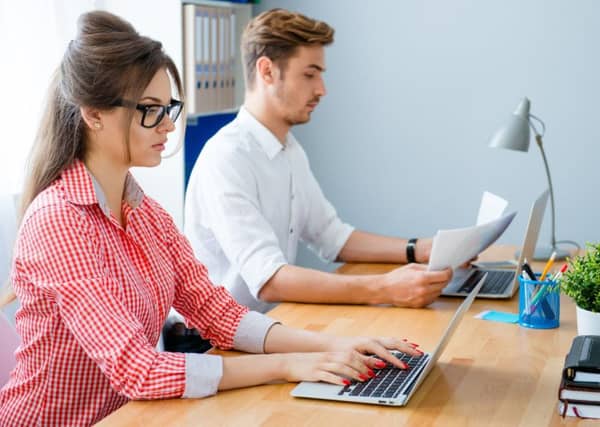 Young business people working at office and typing on laptops