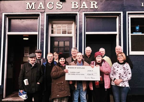 Pictured are Robert Macintyre, quiz compiler (centre) and George and Katy Ross, proprietors of  Macs Bar (far right) with some of the participants of the quiz and Jackie Telford and Lisa McConnell (holding cheque) from the Thomson Court Campus. Photo by Iain Cochrane.