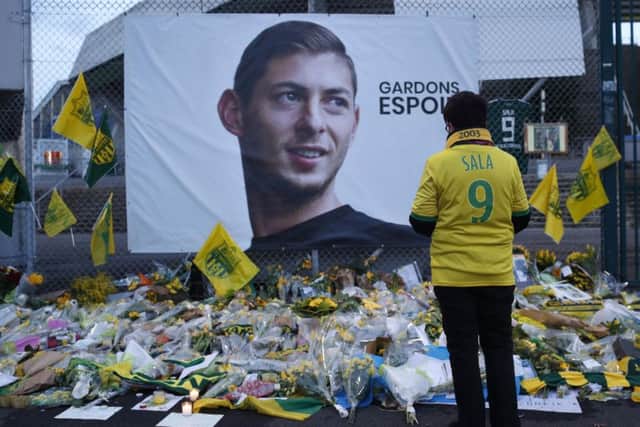 A Nantes fan stops by a poster of Emiliano Sala reading "Let's keep hope" outside La Beaujoire stadium. Picture: AP