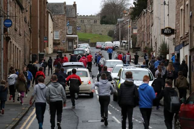 Boys chase the leather ball up the hill past cars during the annual 'Fastern's E'en Hand Ba' event.