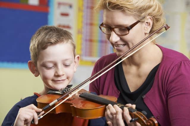 Teacher Helping Pupil To Play Violin In Music Lesson