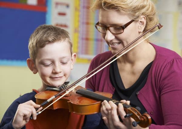 Teacher Helping Pupil To Play Violin In Music Lesson