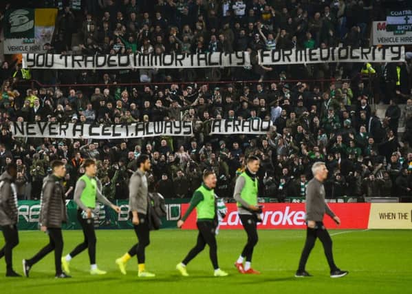 The Celtic subs walk past a banner aimed at former manager Brendan Rodgers. Picture: SNS