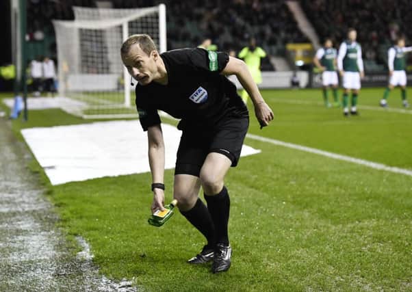 Referee Wiillie Collum removes the bottle thrown towards Scott Sinclair at Easter Road. Picture: Rob Casey/SNS