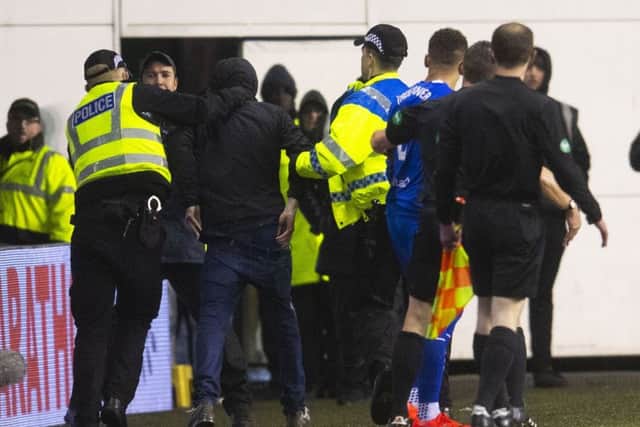 The fan is led away by police after confronting James Tavernier. Picture: SNS