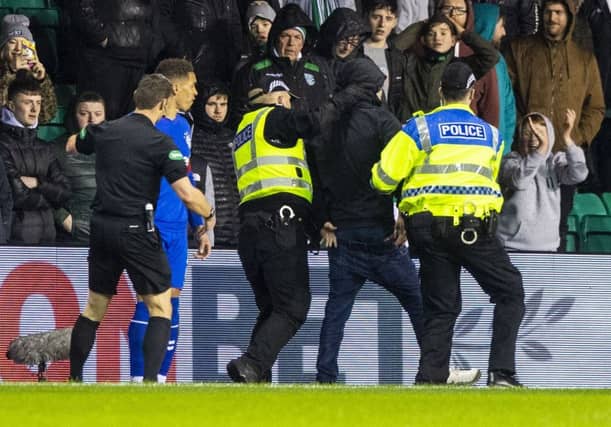 Hibs fan is led away by police after running onto the park to confront James Tavernier. Picture: SNS