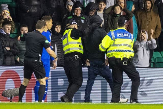 Hibs fan is led away by police after running onto the park to confront James Tavernier. Picture: SNS