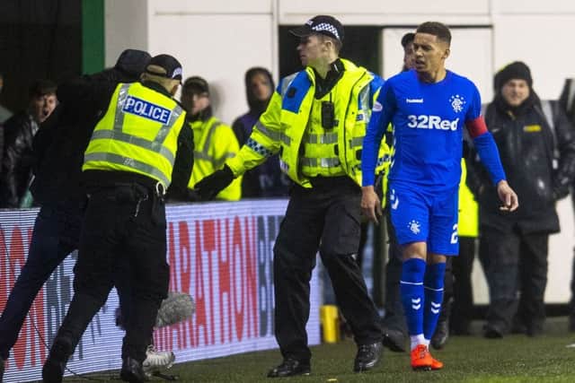 Police lead a supporter away after he confronted Rangers captain James Tavernier on Friday night