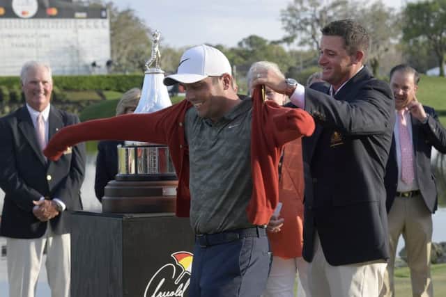 Arnold Palmers grandson, Sam Saunders, right, helps winner Francesco Molinari put on a tournament sweater. Picture: Phelan M. Ebenhack/AP